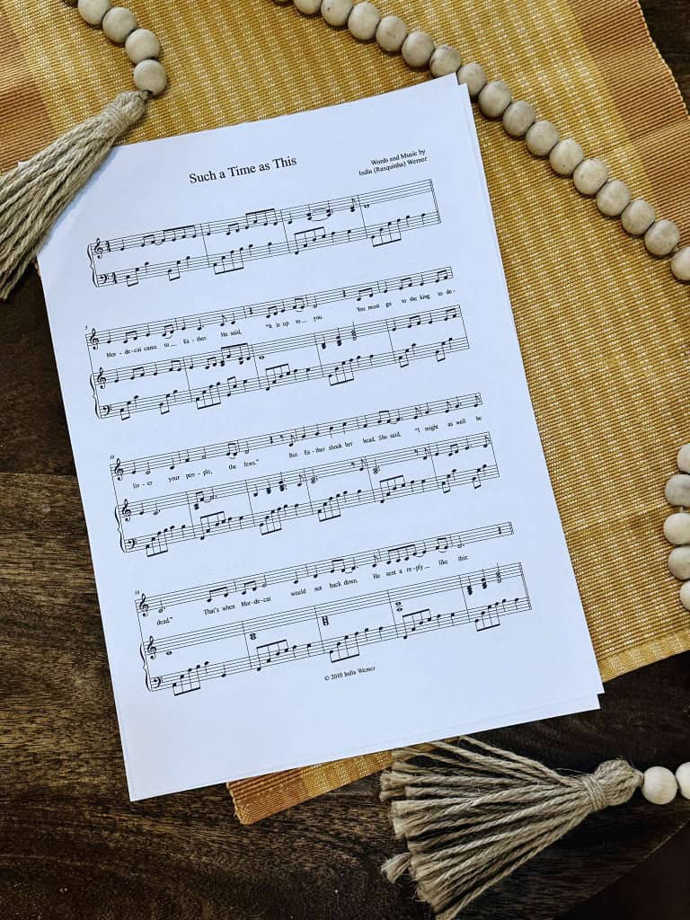 Sheet Music for "For Such A Time As This" laying on a table with a beige placemat and a strand of beads.
