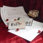 A collection of products including the "Believe" and "Christmas Time" CD's along with the sheet mustic to "A Silent Night" are visible near a model piano and Christmas bulbs.